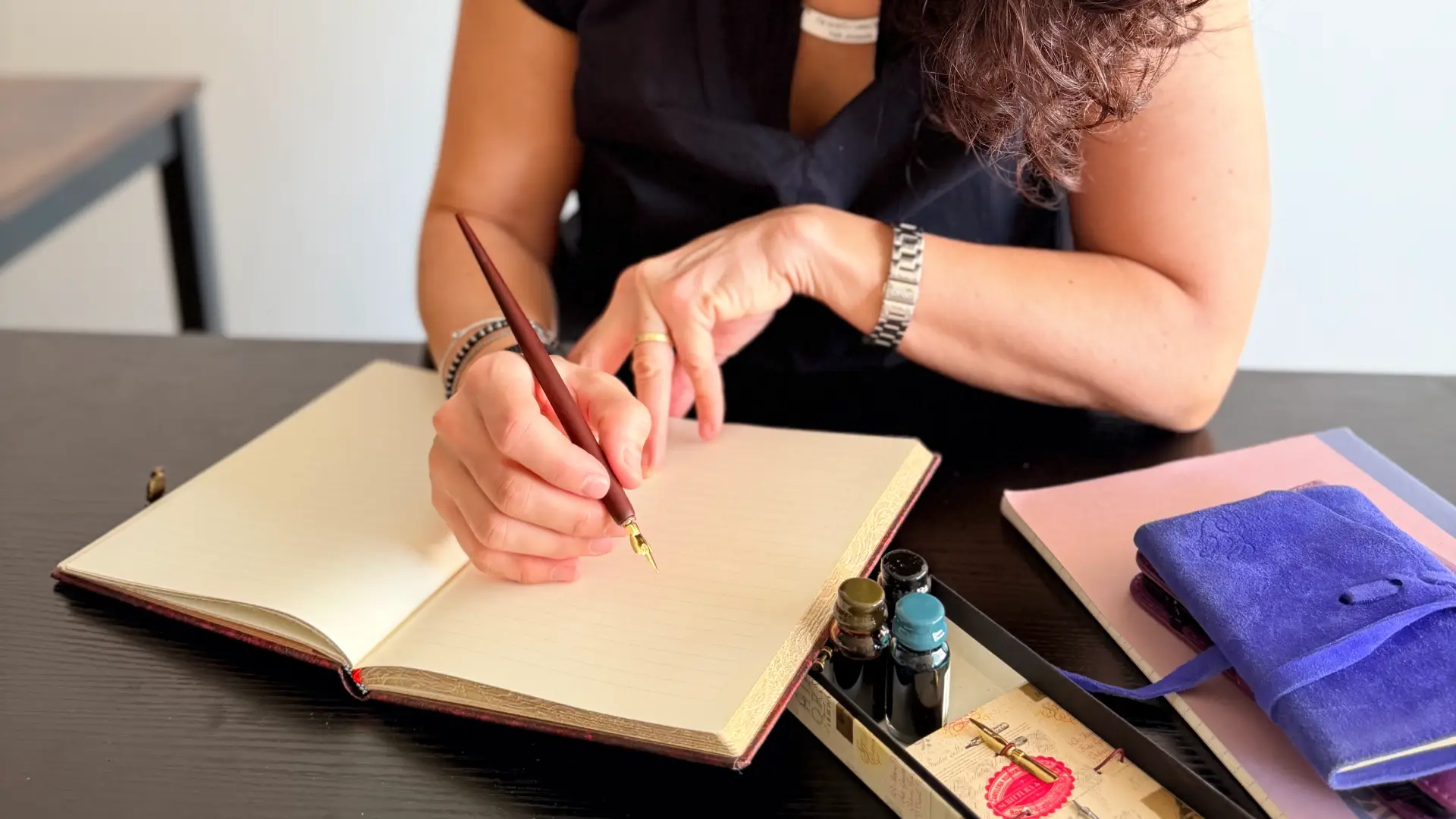 Le mani dell'autrice scrivono con la stilografica su un quaderno intonso: l'immagine descrive l'inizio del processo creativo della drammaturga che si mette a lavoro su un nuovo progetto,